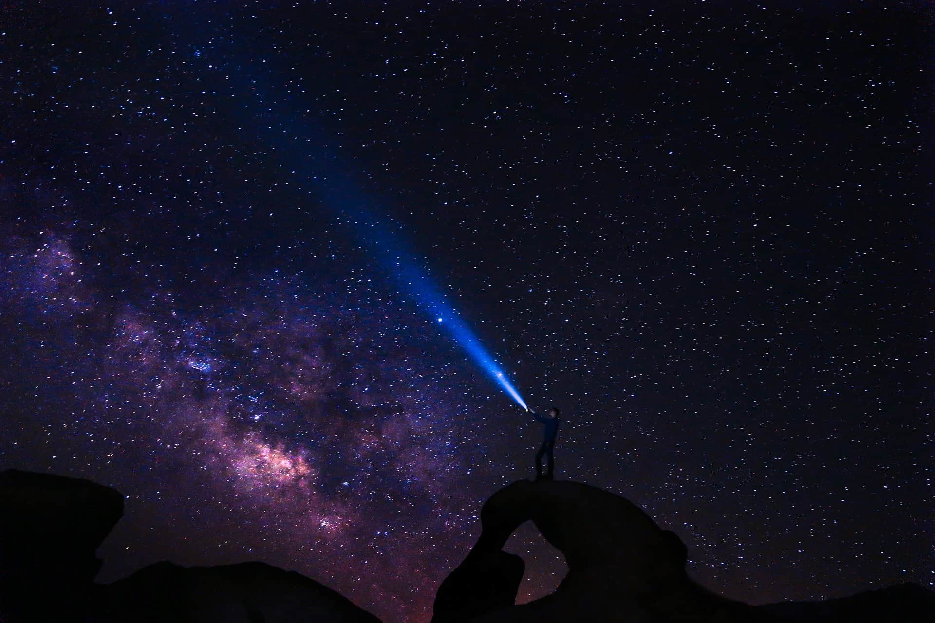 guy standing on a hill trying to see the galaxy