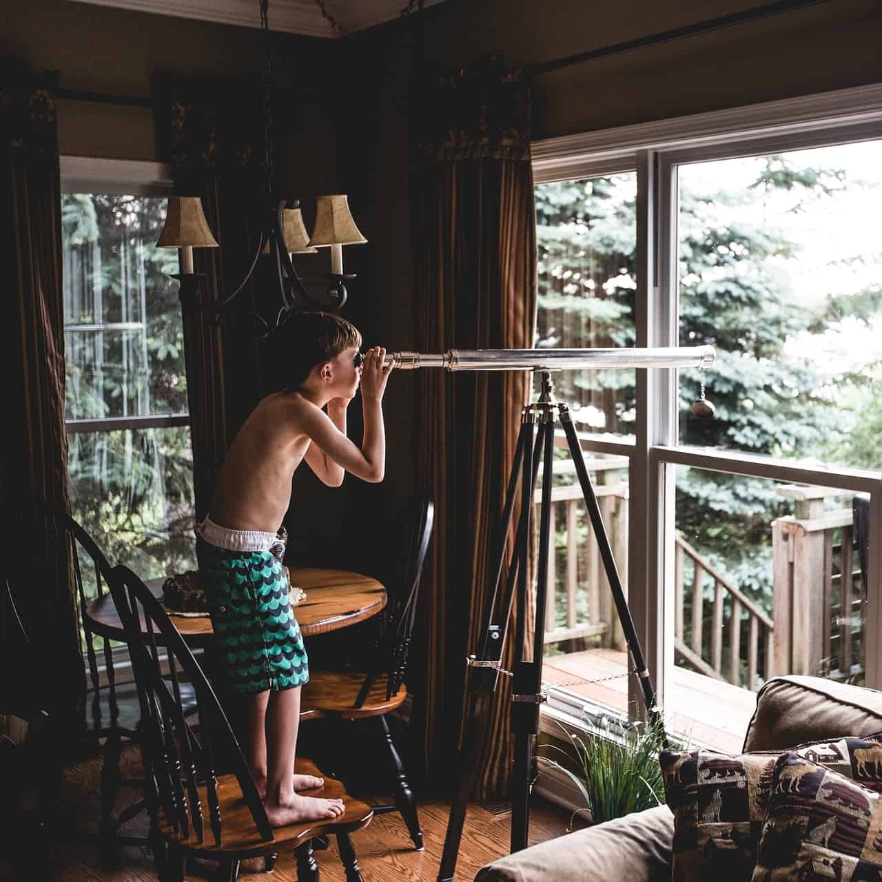 youngster standing on a chair looking through a scope