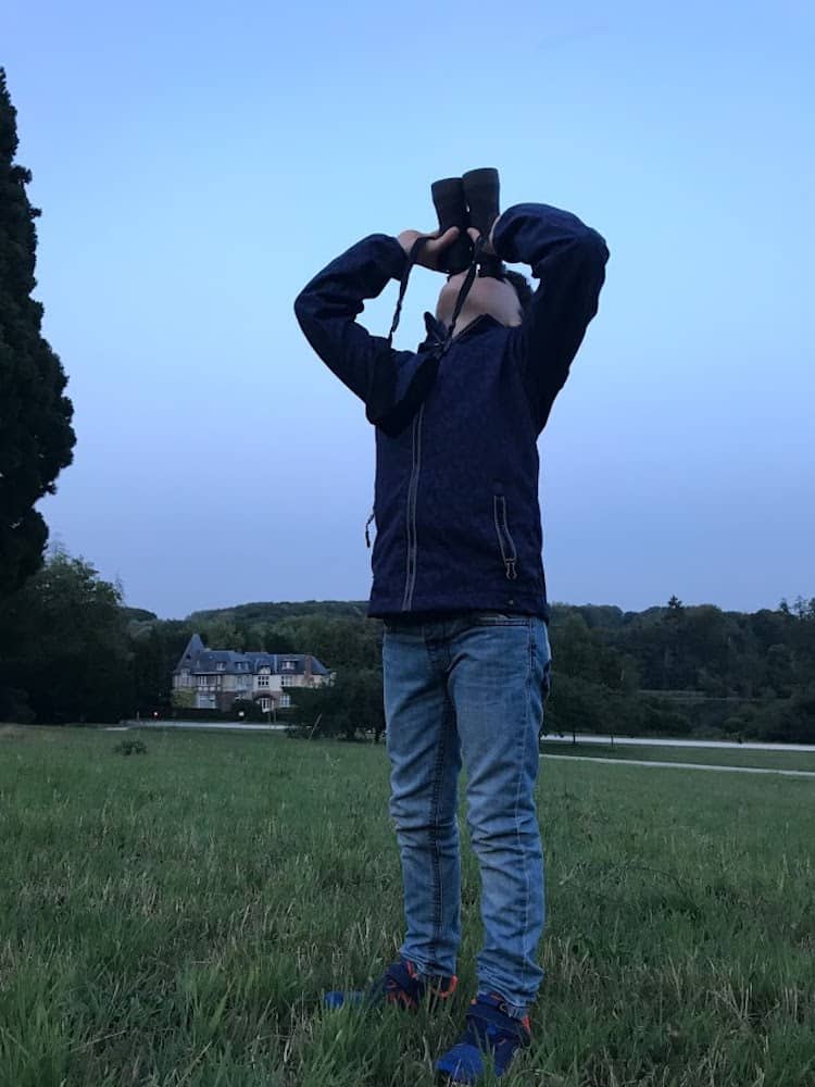 child using binoculars to view the moon on vacation